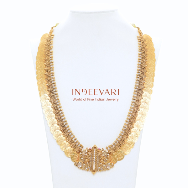 Layered antique-finish gold coin kasumala necklace with embossed Lakshmi motifs on each coin, hand-formed gold bead links, and central nakshi-carved pendant with stone accents